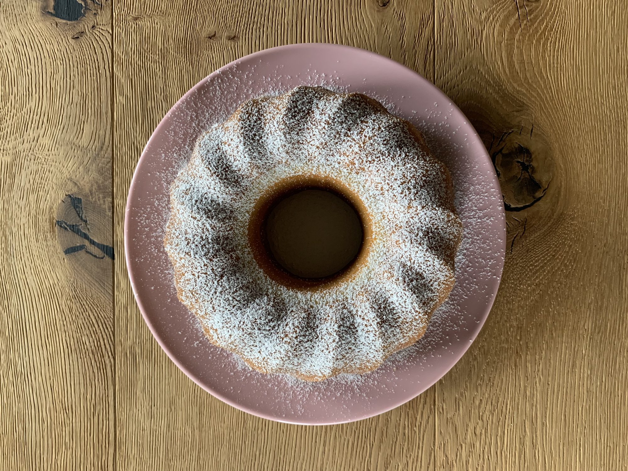 Gugelhupf mit Puderzucker auf rosa Teller